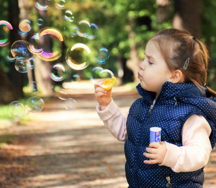 A little girl makes soap bubbles