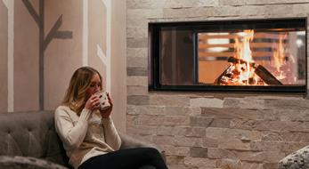 A woman is having a drink by the fireplace